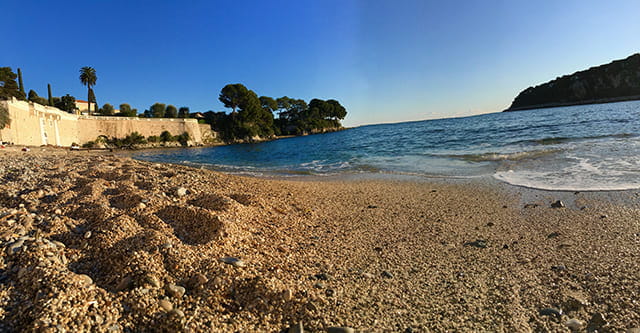 Sandy beach with clear blue sky and ocean waves.