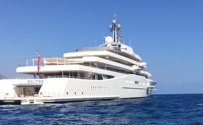 Large white yacht on open sea under clear blue sky.