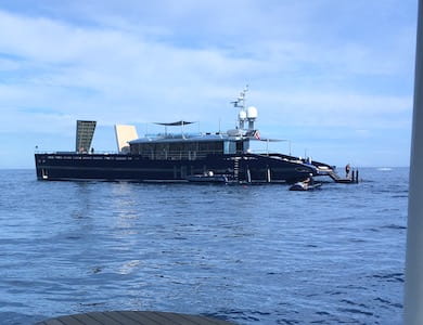 Modern yacht with sleek design on calm blue ocean under cloudy sky.