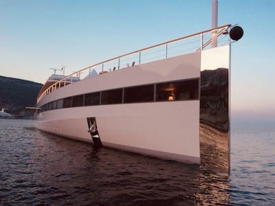 Modern white yacht on calm water during sunset.