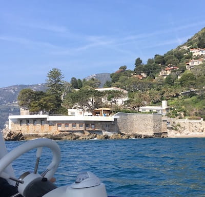 View of coastal buildings and hillside from a boat on the water.