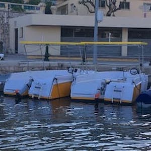 Four small boats docked on calm water near a building.