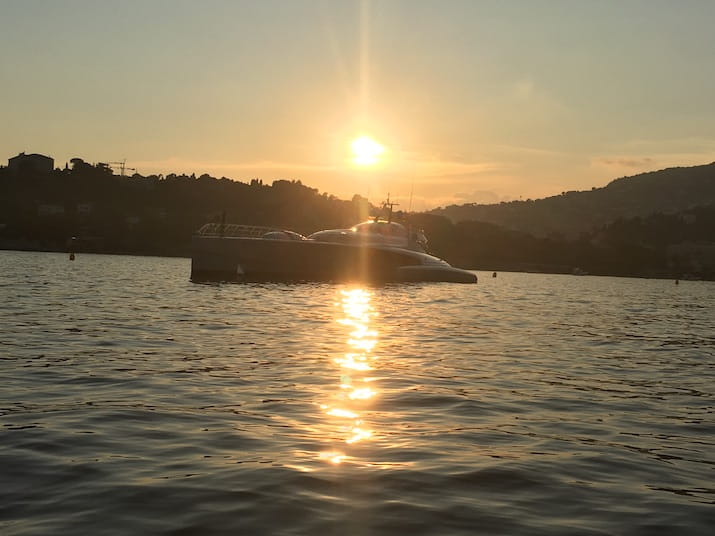 Boat on water at sunset with hills silhouetted in the background.
