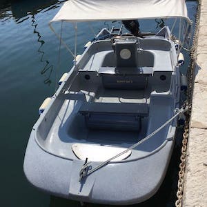 Small motorboat docked, covered with white canopy.