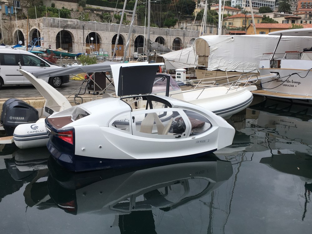 White futuristic boat with canopy docked in a harbor.