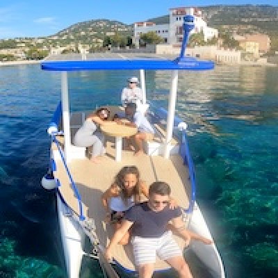 People enjoying a boat ride on clear water near scenic coastline.