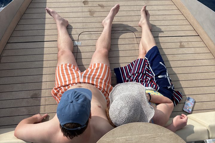 Two people relaxing on a boat deck near the water.