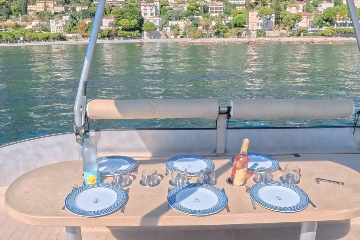 Table set on boat with lake and hillside view in background.