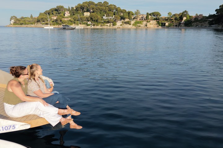 Two people sitting on a dolphin-watching bow, overlooking a calm bay.