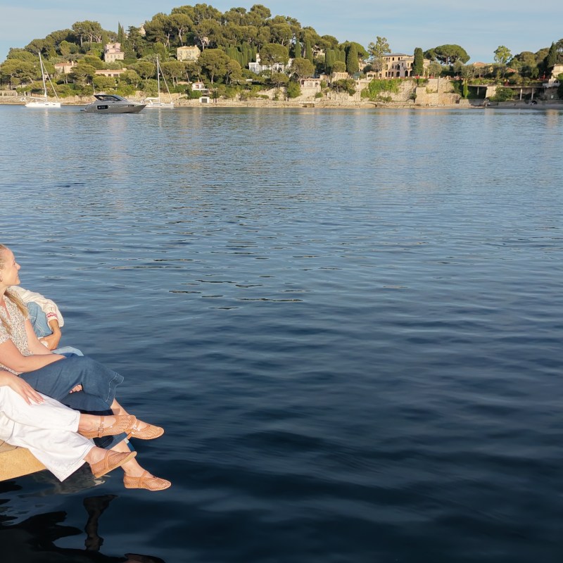 Two people sitting on a dolphin-watching bow, overlooking a calm bay.
