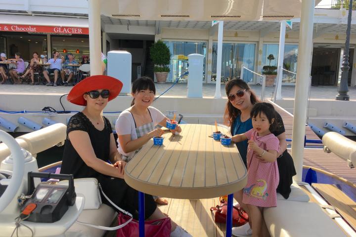 Four people sitting at a table on a boat, eating ice cream in a sunny marina.