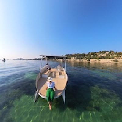 Person relaxing on a boat in clear water under a blue sky.