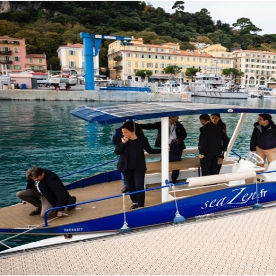People standing on a docked blue and white boat near colorful seaside buildings.