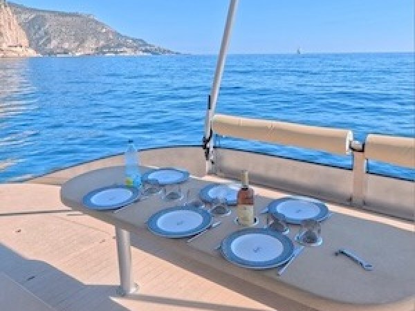Set table on a boat overlooking the ocean with distant cliffs and clear blue skies.