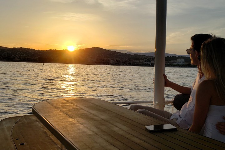 Couple sitting on a boat watching sunset over the water.