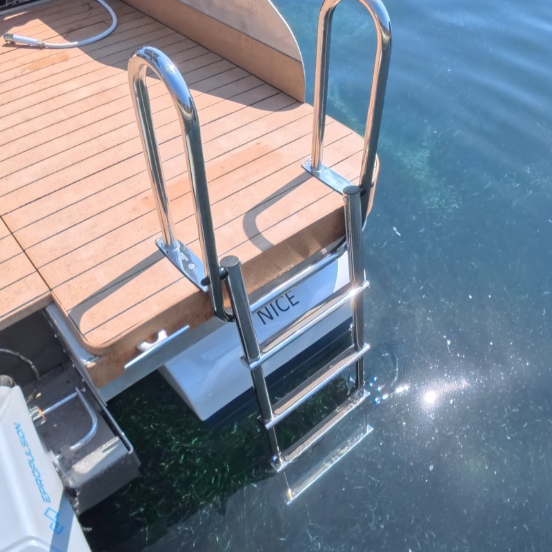 Boat with metal ladder leading into clear water.