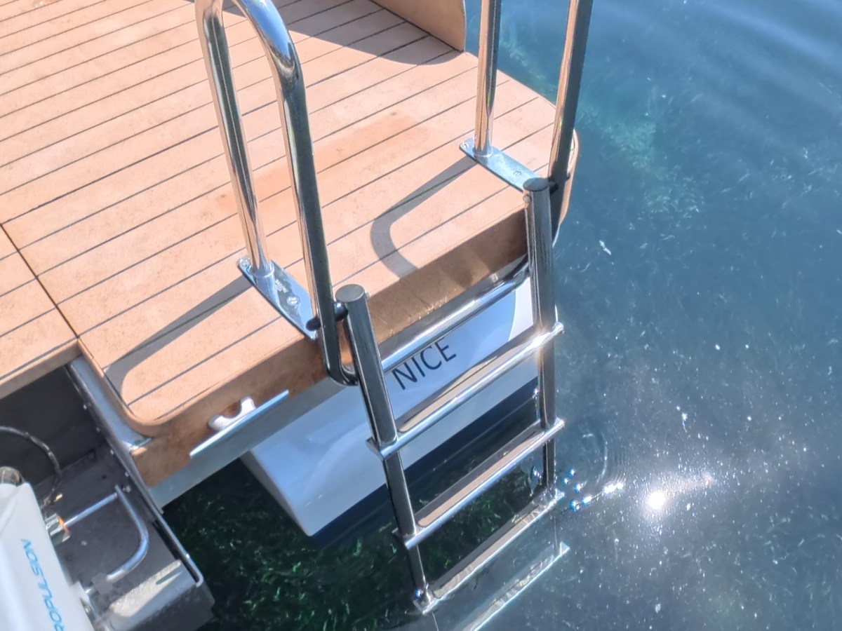 Boat with metal ladder leading into clear water.