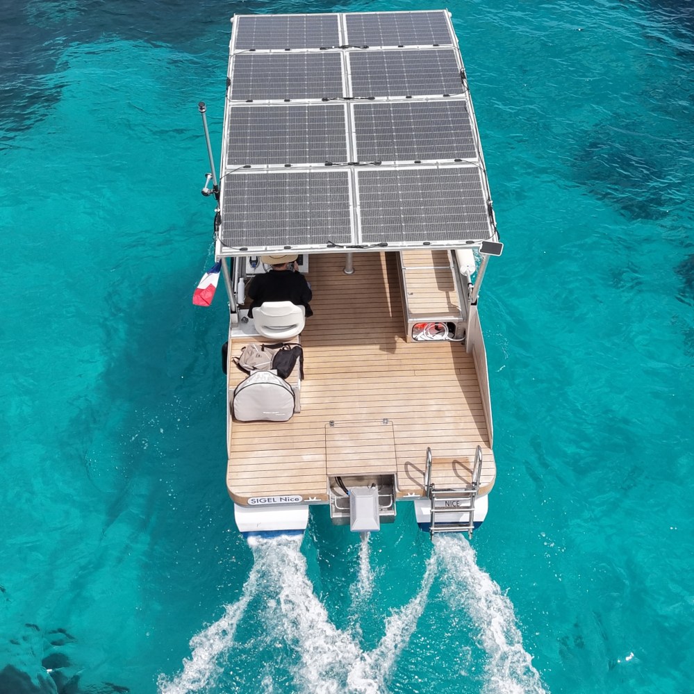 Solar-powered boat on clear blue water, rear view.