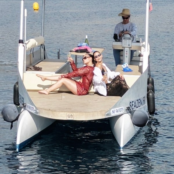 Two people relaxing on a boat in calm waters, one operating the controls.
